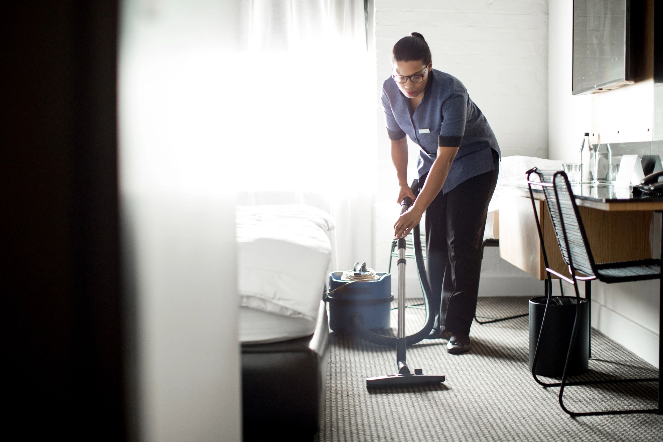 Professional cleaner vacuuming carpet in a commercial room